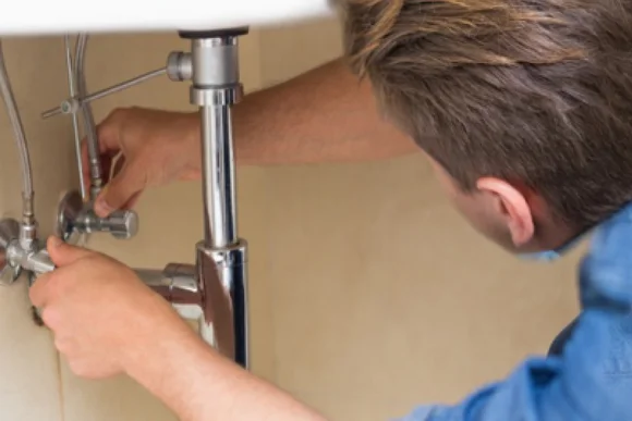 Person repariert Rohre unter Waschbecken